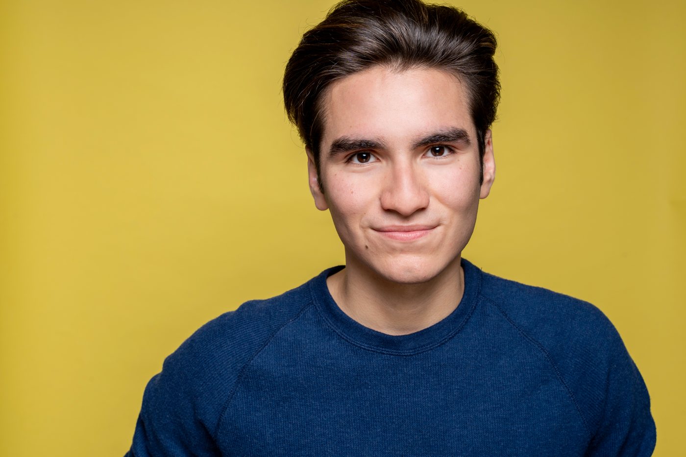Headshot of a young actor on a yellow backdrop