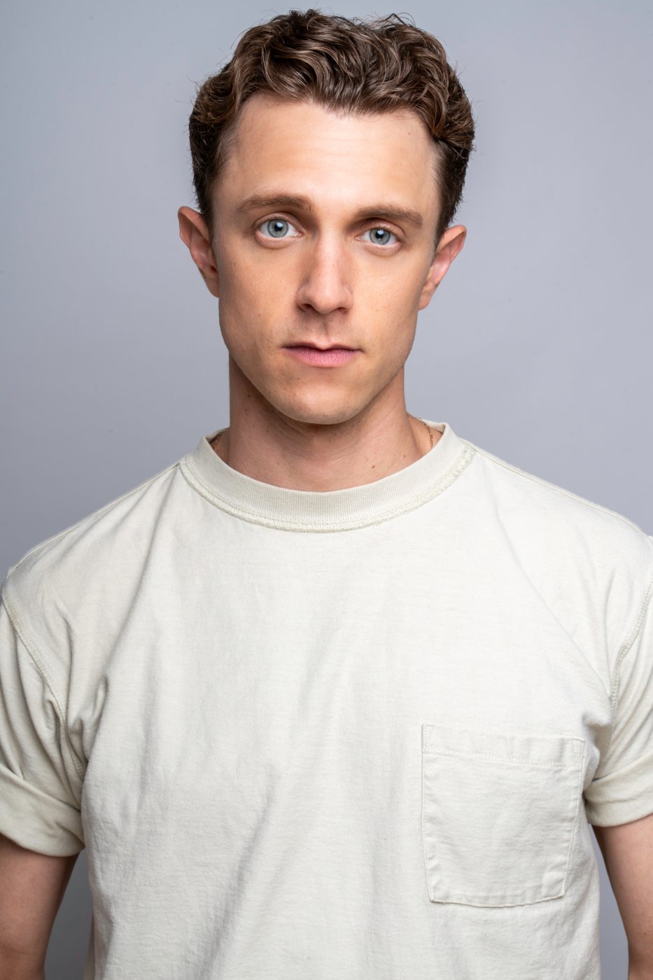 Headshot of an actor in a white tee on a gray backdrop