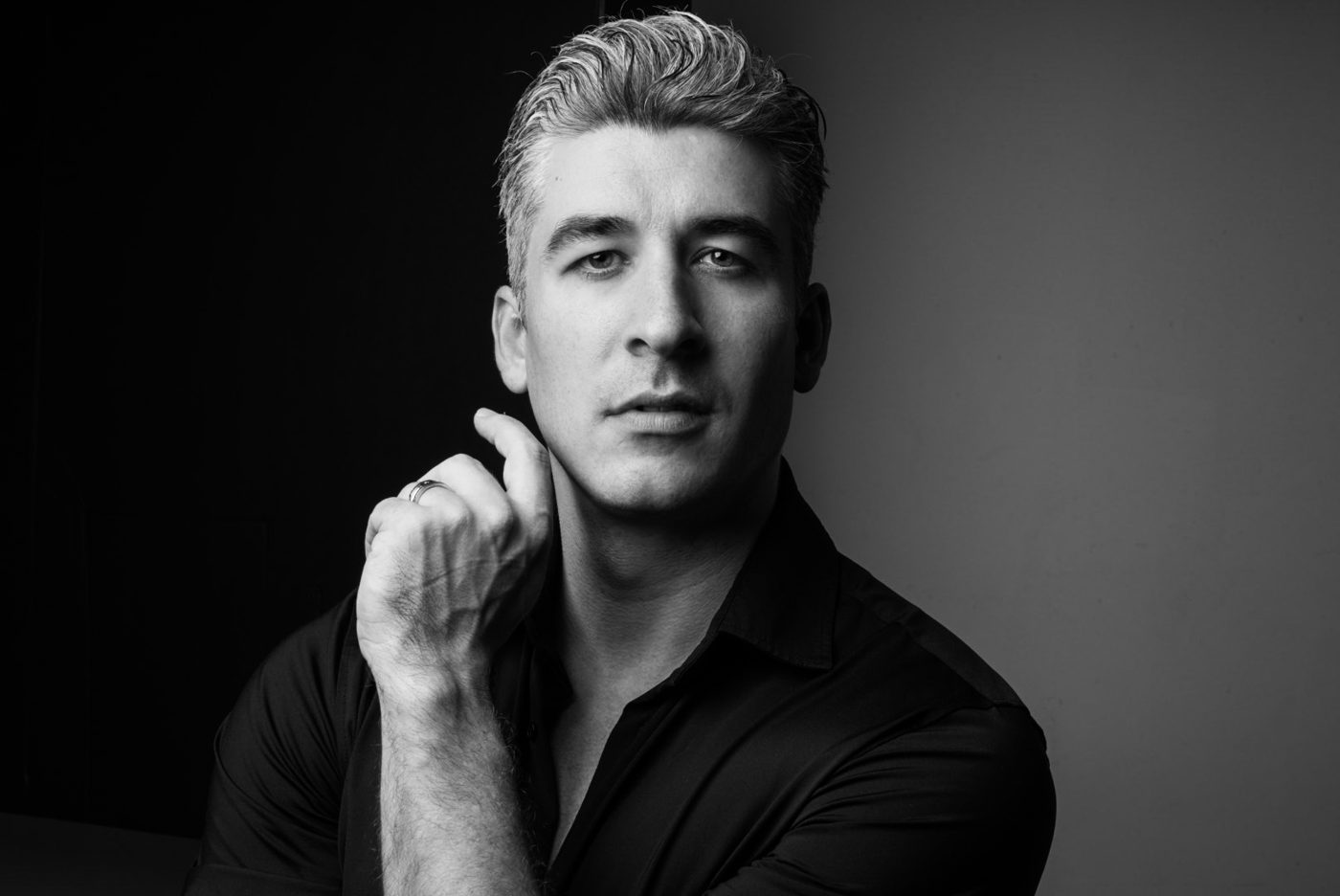 Black and white portrait of a man with his hand at his neck