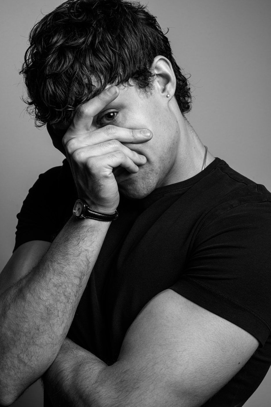 Black and white portrait of a man covering his face with his hand