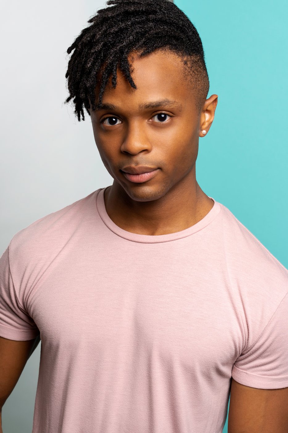 Headshot of an actor in a pink tee
